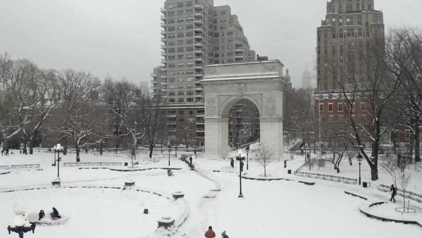 Rising aerial over Washington Square Park arch white winter snow - blizzard snowing in NYC