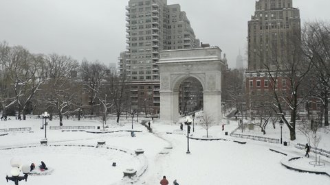 rising aerial over Washington Square Park arch white winter snow - blizzard snowing in NYC