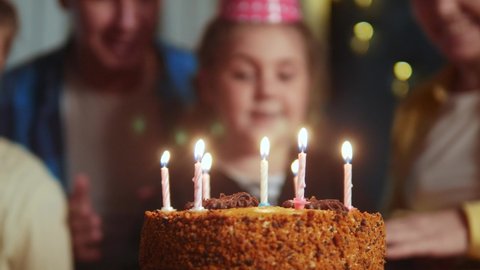kid birthday. little girl blows out the candles on dream the cake in a circle of happy family. celebration birthday kid concept. friendly happy family celebrating birthday a lot of people