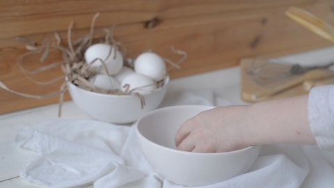 kids hands breaking a raw fresh egg on the white wooden table. Selective focus. Natural healthy food concept
