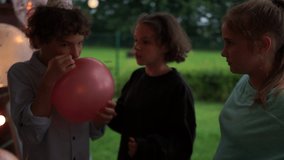 A boy and a girl are holding a balloon with helium. Breathe in the air and speak in a thin voice. Funny video, have fun