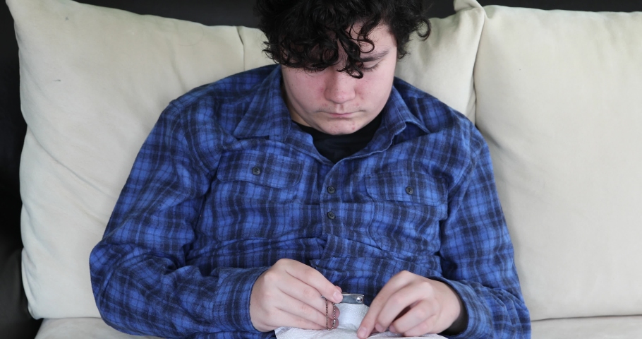 Young man cutting his fingernails