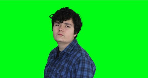 Teenage boy with serious face looking at camera at chroma key background