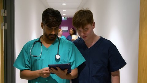 Medical Staff Using Tablet Walking In Corridor