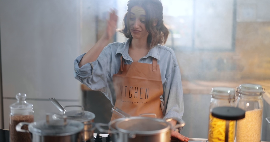 Tired and sad housewife standing hopelessly in a smoky kitchen from burnt food. Exhaustion from household chores and home routine concept | Shutterstock HD Video #1066728796