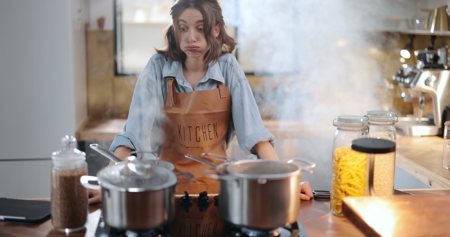 Tired and sad housewife standing hopelessly in a smoky kitchen from burnt food. Exhaustion from household chores and home routine concept | Shutterstock HD Video #1066728865