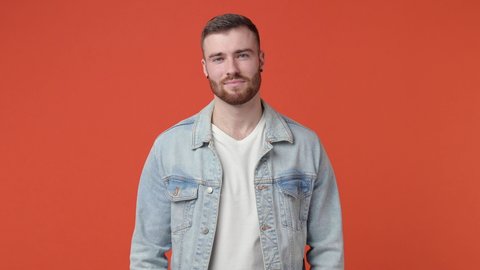 Smiling laughing handsome bearded young man 20s years old in casual white t-shirt denim jacket isolated on orange color background in studio. People sincere emotions lifestyle concept. Looking camera