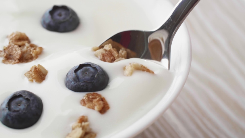 Yogurt with granola and blueberries. Adding granola and fresh blueberries into greek yogurt. Healthy breakfast or snack meal | Shutterstock HD Video #1066729996