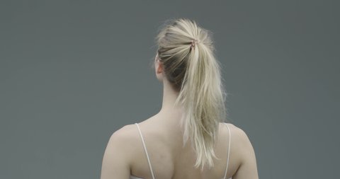 Pretty young blond girl take off scrunchie from hair satisfied with dyed hairs condition, morning routine, back view