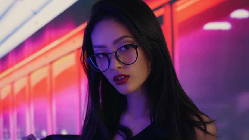 Fashion beauty shooting of gorgeous Asian model. Young beautiful woman in black jacket posing over night city dramatic red and blue neon background