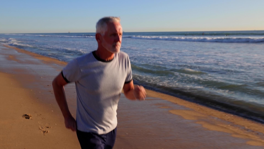64 year old man getting his exercise at the beach at sunset.