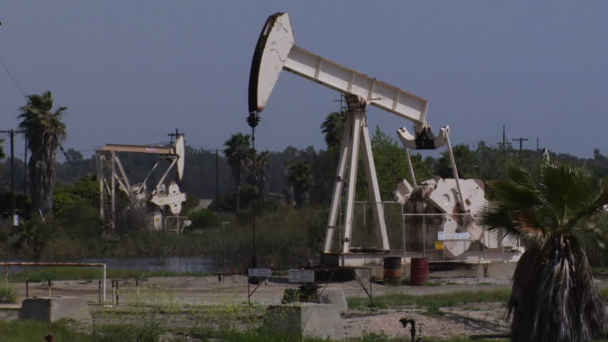 wide shot of an oil well pumping in Long Beach, CA