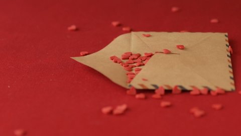 Red heart shaped sugar confetti falling down in valentine greeting card on red background slow motion. Romantic love, affection Saint Valentine's Day, Mothers Day, wedding preparation design concept
