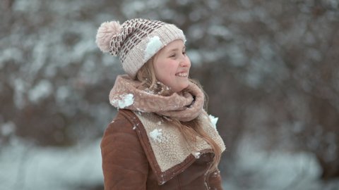 Portrait of modern girl outdoors in the city park in winter in a knitted hat and sheepskin coat.