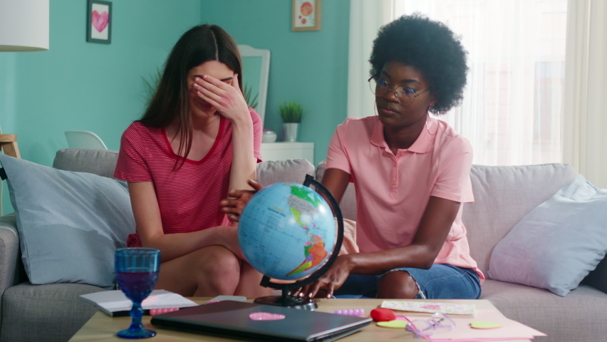 Young women, best friends, addicted travelers, have fun playing with globe, trying to guess next travel destination, make travel list for the next season, happy and excited, Foreground, Slow motion.