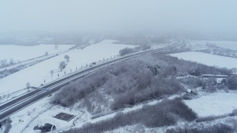 Dangerous driving conditions, heavy snow falling over freeway, aerial drone shot