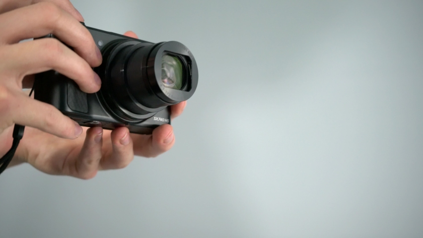 Using, zooming, and taking picture with small superzoom point-and-shoot camera from Canon with white background studio shot