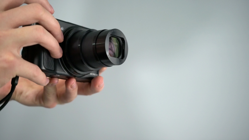 Using, zooming, and taking picture with small superzoom point-and-shoot camera from Canon with white background studio shot