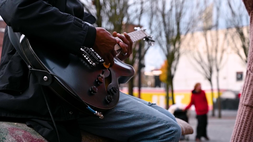 Slow motion of street performer playing live guitar and people enjoying the rhythm. Close up side view.
