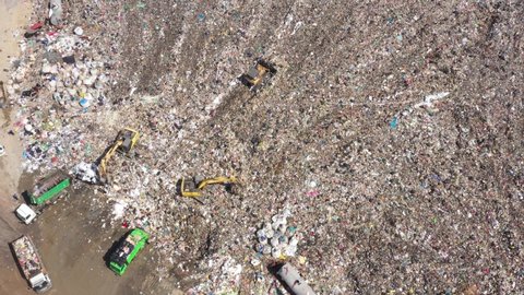 Aerial top view of A Huge Waste, garbage, dump, rubbish landfill. A landfill compactor, group of workers sort out the garbage in the landfill. Trash trucks dump waste polluting products.
