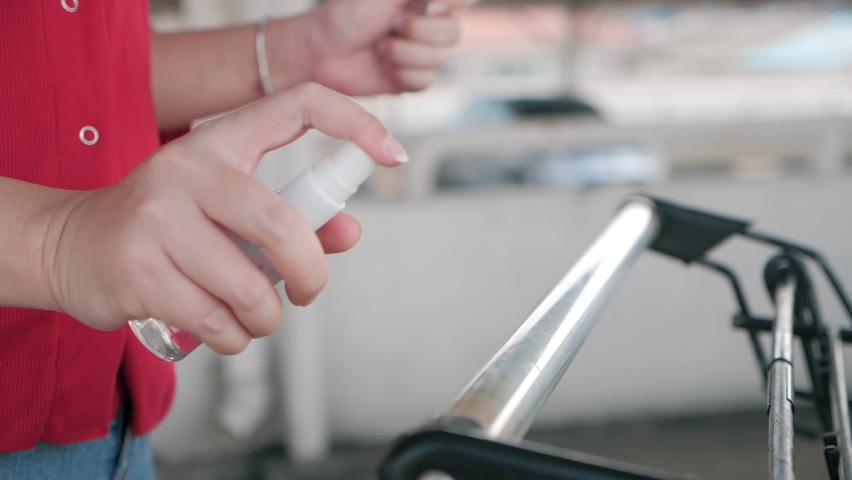 Hands of woman using spraying alcohol antiseptic,disinfecting spray,cleaning on shopping cart,trolley handle,protection during Coronavirus pandemic, Covid-19, wipe clean the surfaces with disinfectant