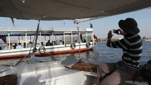 Chinese tourist taking photos on a felucca sailing in the Nile River in the afternoon sunset, Aswan, Egypt, 2020 02 02