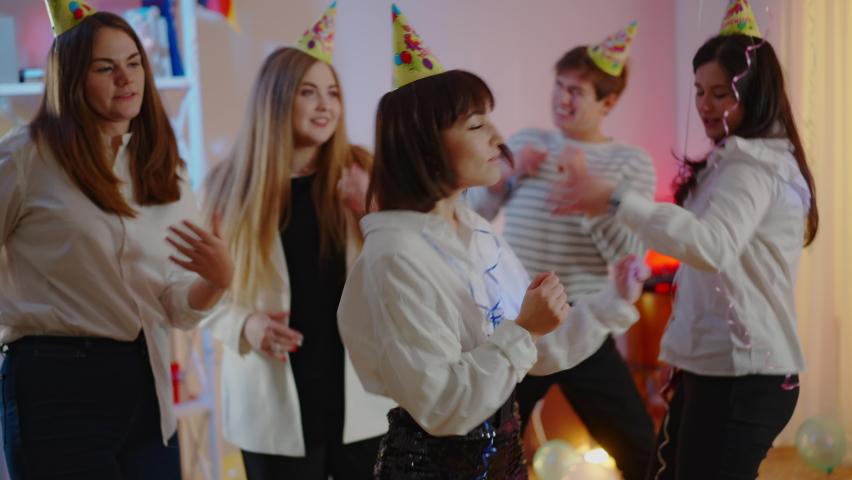 Relaxed group of friend dancing at birthday party as young woman sneezing and people running away. Scared Caucasian millennials celebrating on coronavirus pandemic. Royalty-Free Stock Footage #1066760455