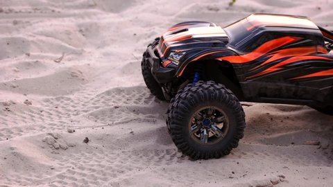 RC car starts drive with splashes on the sand. Radio controlled monster truck model close-up.