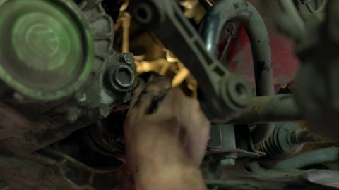 19.04.2019 - Kyiv, Ukraine. Close up dirty hands of screwing something in a car engine mechanism. Stained hands of a mechanic working in carservice center.