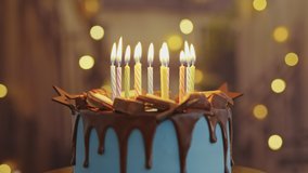 Birthday Cake with Burning Candles, chocolate glaze is Rotating on Stand on Table in House. Bright Dessert for Child's Birthday Party on Background of Bokeh Light Bulbs Garlands. Family. Childhood - Powered by Shutterstock - Get 15% off with code: PIKWIZARD15