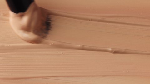 beige smear of tonal foundation cream close up, smudge with a brush, beautiful pastel texture, cosmetic product for make up