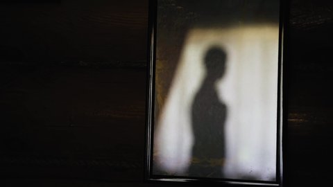 The silhouette of the guy dressing in the room is reflected from the mirror surface. Distorted silhouette in the form of a shadow