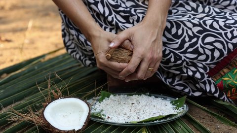 Woman hand grating fresh raw coconut cut open in half 4K slow motion video , footage of Indian Kitchen , Kerala India. organic coconut farm, fresh grated for making coconut milk , oil