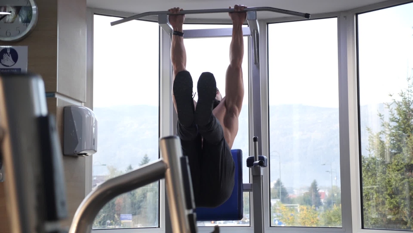 Slow motion Raising feet up to bar on gym bar, attractive muscle man exercise and train in gym. | Shutterstock HD Video #1066781119