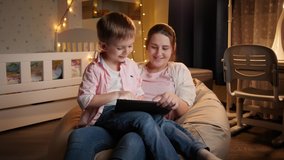 Smiling mother with little son sitting in bean bag at night and sing tablet computer. Concept of child education and family having time together at night. - Powered by Shutterstock - Get 15% off with code: PIKWIZARD15
