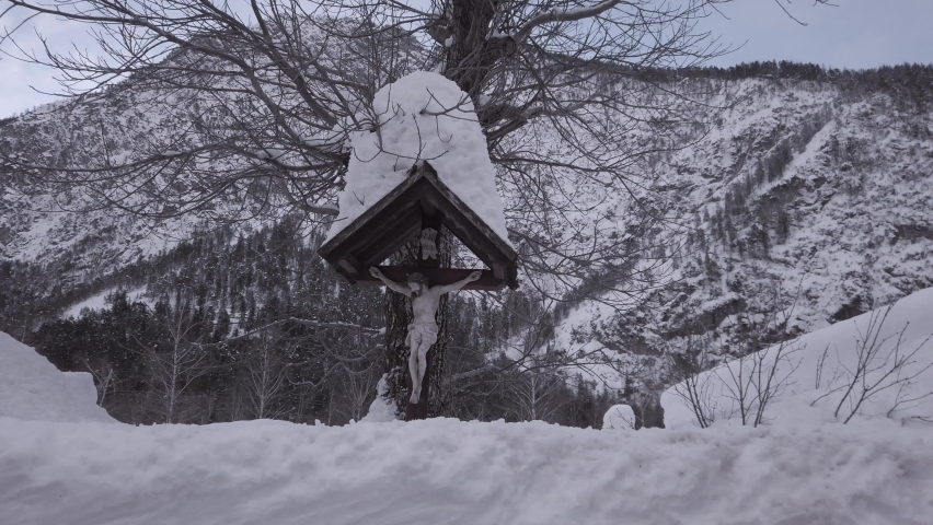 Crucified Jesus Christ covered by snow in harsh winter in Osttirol.