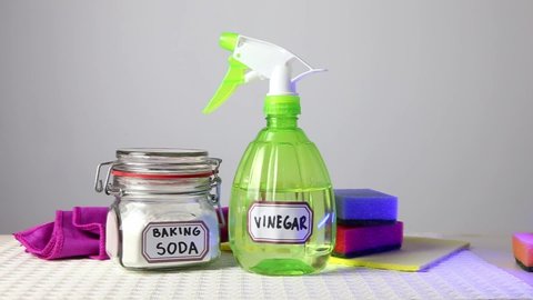 Using baking soda Sodium bicarbonate and white vinegar for home cleaning. White vinegar in spray bottle and baking soda in glass jar.
