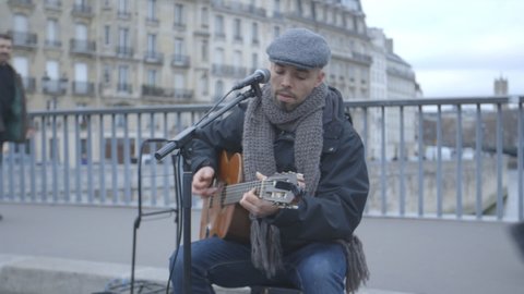 PARIS, FRANCE - DECEMBER 2015: A guitarist busking on the  Pont Saint-Louis bridge over the River Seine in Paris.