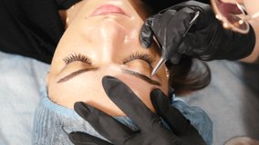 Eyebrow shape correction. woman plucking her eyebrow hair using tweezer. Professional styling, 4 k video