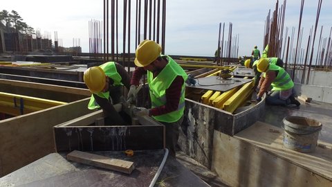 Batumi, Adjaria, Georgia - 02.01.2021: Builders in helmets work at a construction site. Workers hammer nails.