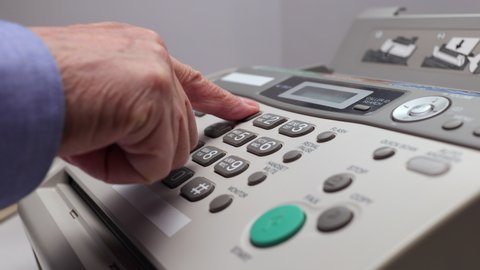 Men's Hand Dials On The Number Buttons On The Old Fax Telephone. A Man's Hand Picks Up The Phone And Dials A Phone Number On The White Keyboard Of A Landline In The Office.