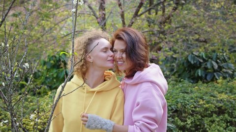 lesbian couple hugging in a sakura garden. Two women share love and support while holding hands. Gay Family. LGBT concept of friendship. cinematic chot bmpcc 6k
