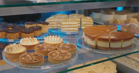 Showcase with desserts for sale in Pastry Shop. A pastry chef puts freshly cakes in show window.