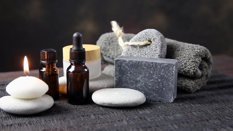 Set of different man spa essentials, beard oil, gray soap, natural loofah sponge, candle, aroma oil on wooden and black background. Father, brother or husband gift idea concept.