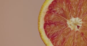 Close up orange juice flows on natural fruit on pink studio background with copy space, fresh delicious vitamins