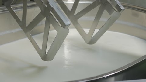 The cheese maker adds rennet to the milk coagulation tank. measures the temperature of milk in the tank with an electronic non-contact thermometer. Mxer mixes the mass