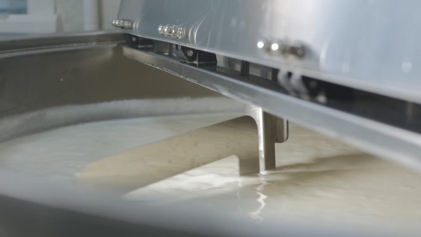 Stirring milk in a cheese dairy with a special mixer in a large vat. Pasteurization and mixing of cheese milk. Cheese production in a small family cheese dairy | Shutterstock HD Video #1066800922