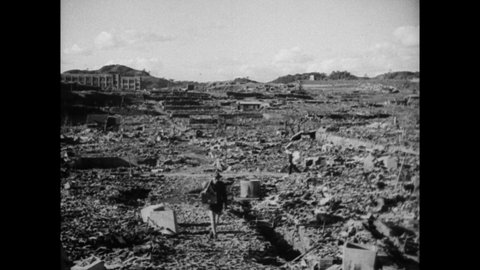 NAGASAKI, JAPAN 1940s: Map of Nagasaki city with circle of bomb strike. Destroyed houses and foundations sit on hillside. Destroyed and burned trees and poles stand near rubble of homes.