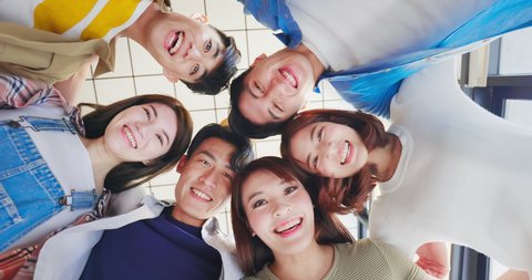 slow motion - Directly below shot of asian young friends forming huddle and their head forming a circle indoor