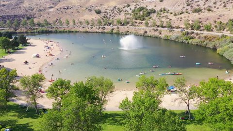 Drone gliding over a public water oasis in Lucky Peak State Park with people playing in the water.